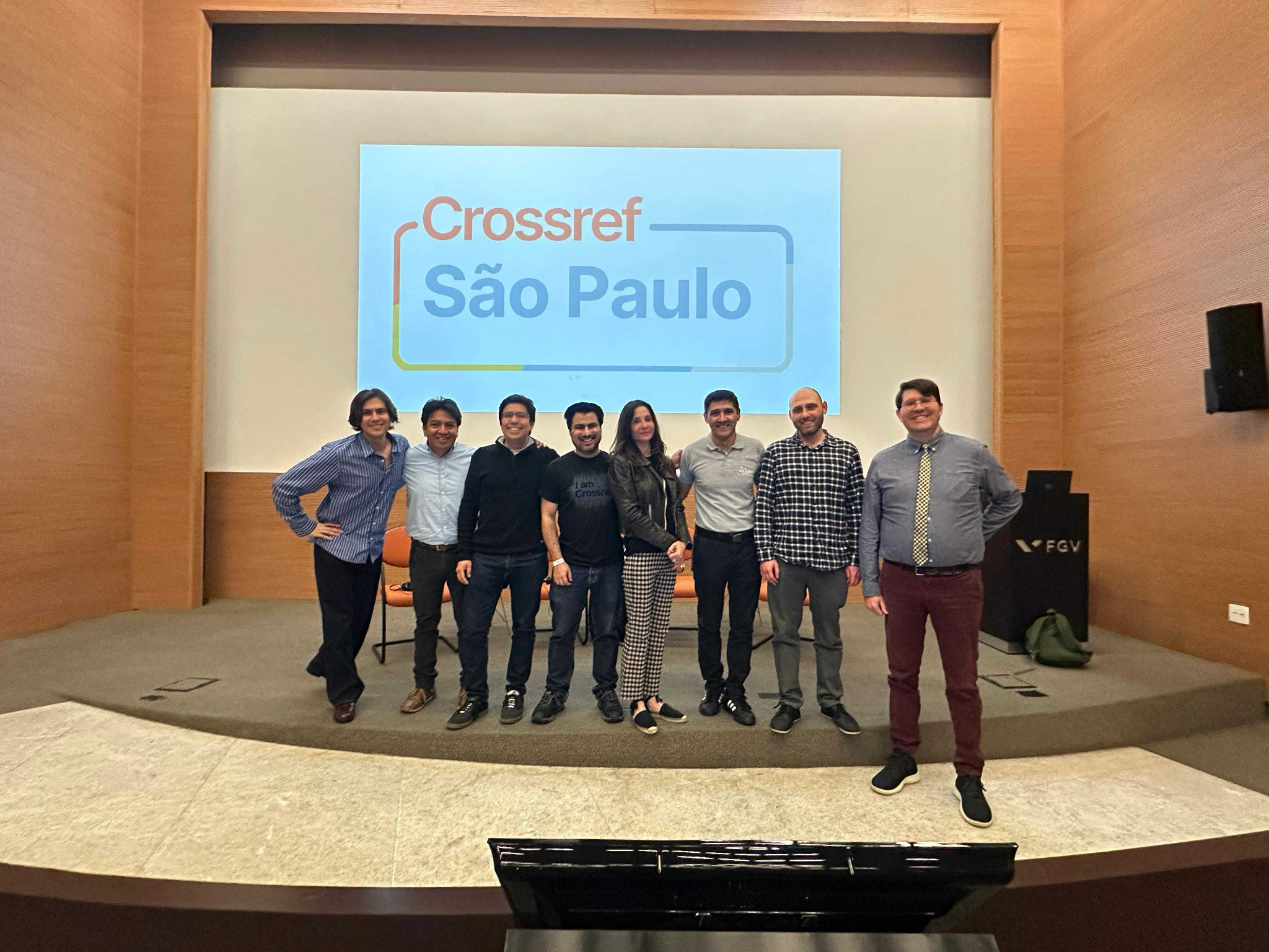 Group photo of Crossref staff and ambassadors on stage at a “Crossref São Paulo” event, likely held at an FGV venue.